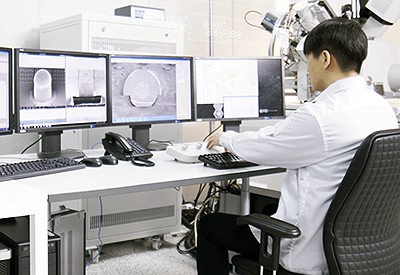 Engineer sitting at desk looking at monitors with package characterization simulations on screen